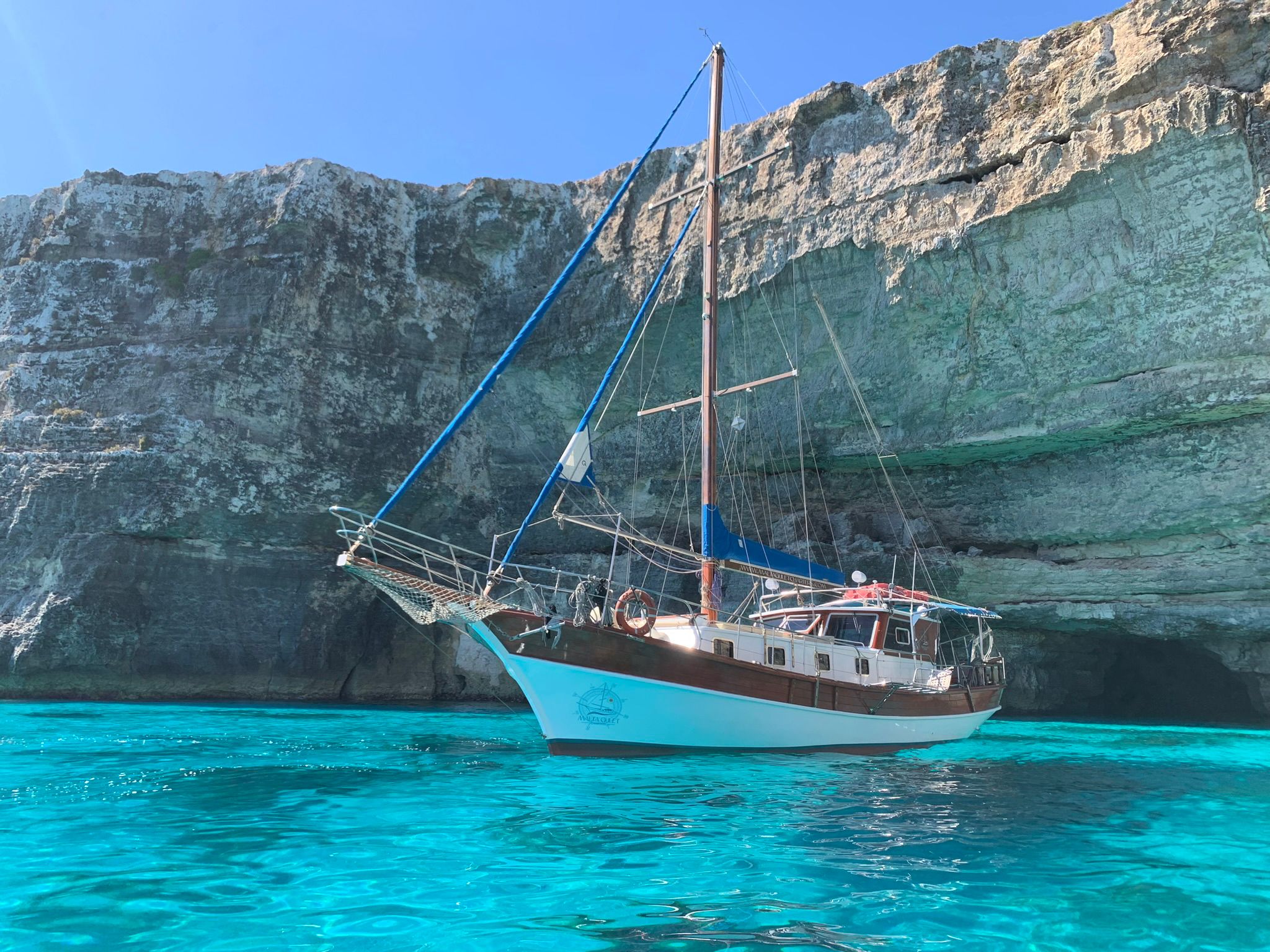Gullet anchored near dramatic cliffs in crystal-clear waters