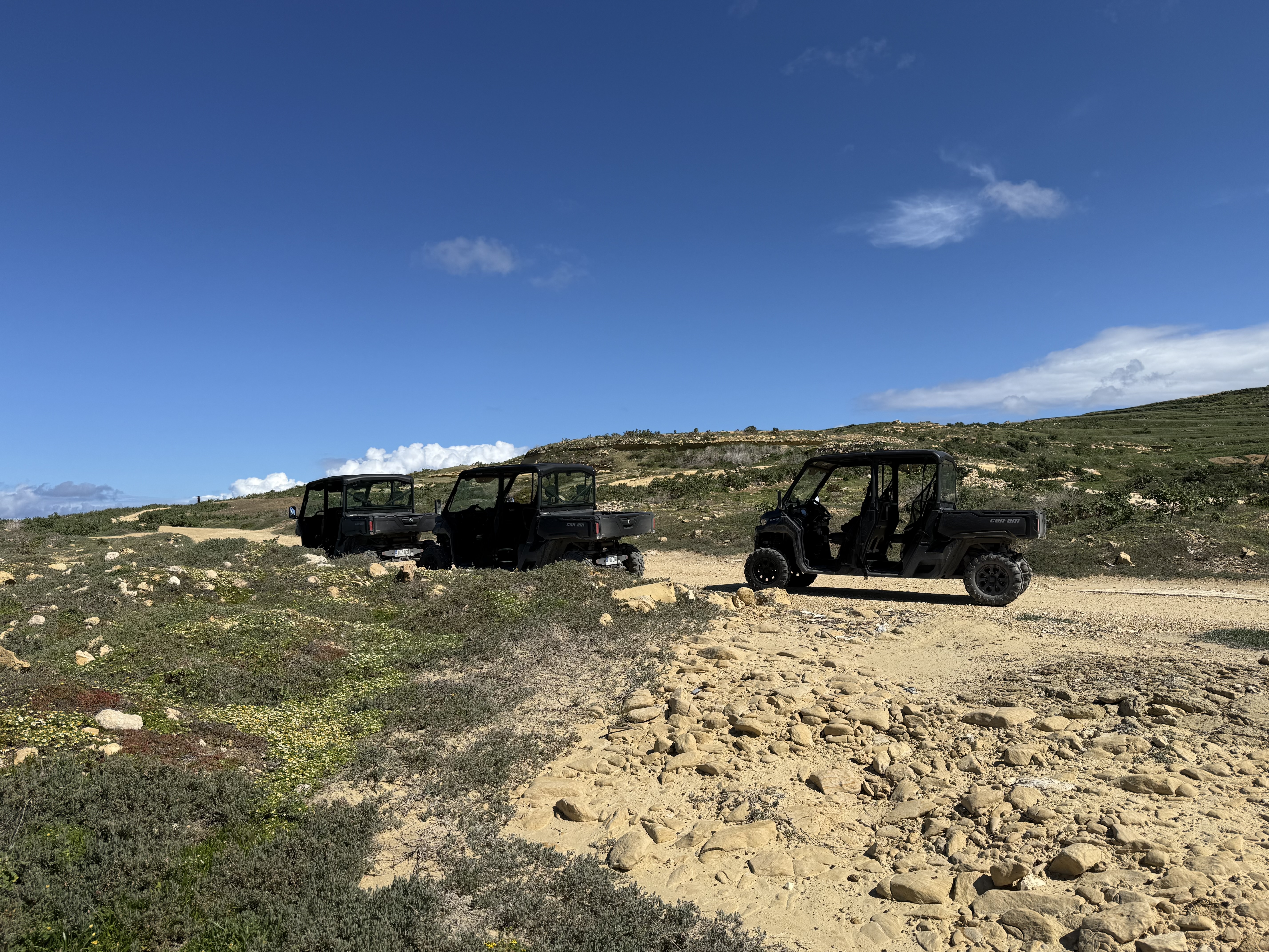 Three Can-Am Traxter jeeps on rocky Gozo terrain under a bright blue sky